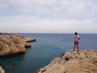 Deniz, Kıbrıs, Protaras, Mayıs 2018 görüntüleyin. Güzel mavi deniz. Kayalar ve dağlar. Bu manzara karşısında gelen nefes alıyor. Bir adam bir kaya üzerinde sırtında ve şu güzelliğe bakar