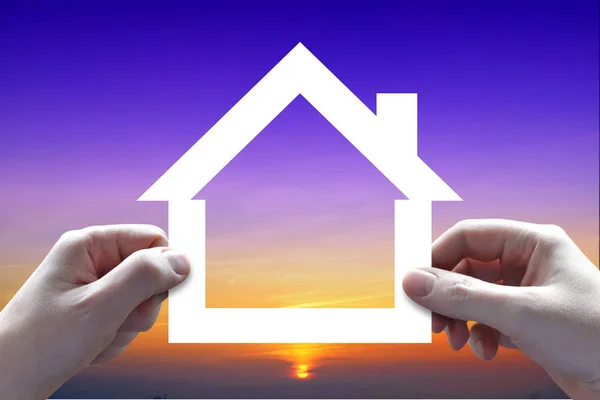 Концепция страхования дома, руки, небо заката на заднем плане — стоковое фото