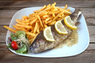 Fırında balık - alabalık, salata ve patates kızartması tabakta