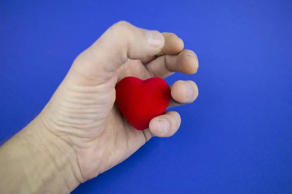 Heart in the male palm on a blue background, there is free space to fill the text