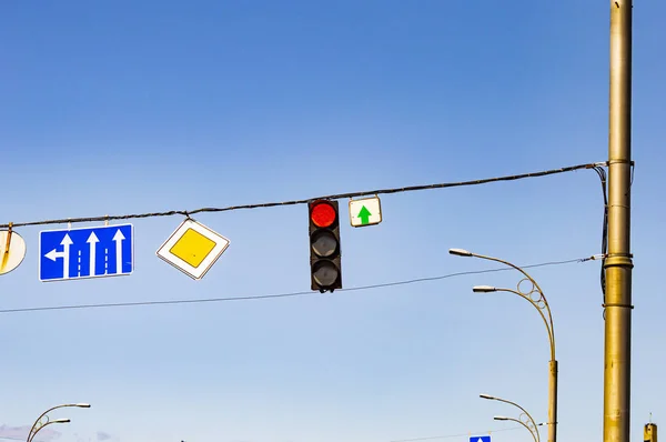 Traffic light with traffic signs on a background of blue sky.