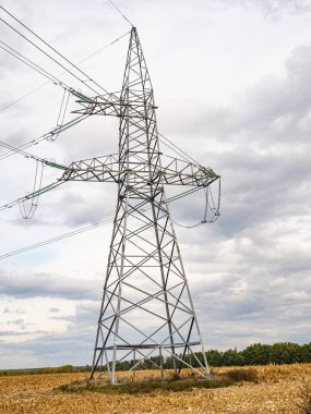 Bulutlu gökyüzüne karşı yüksek voltajlı enerji aktarımı..