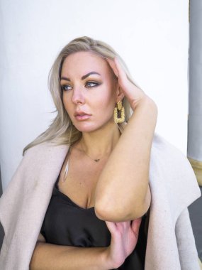 Beyaz bir duvarın arkasında sarışın bir kız..