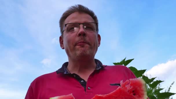 戴眼镜的人吃红色西瓜 人类的手大家好食物 食物摄入 一个男人西瓜果 红色西瓜 维生素广告视频剪辑 厨房的工具 — 图库视频影像