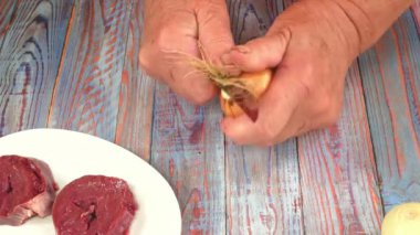 Mutfak bıçağıyla soğan kabuklarını soyuyordu. Yemek fotoğrafı. Mutfak tarifi. Bulaşık menüsü. Ev mutfağı. Yemek pişirmek. Sebzeler. Mutfak aleti. Promosyon videosu. Atıştırmalık.