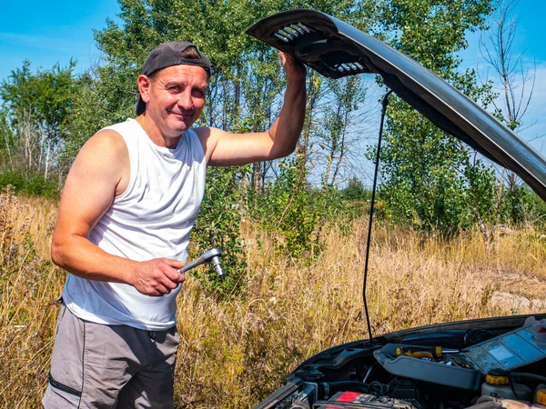 A man repairs a car with a working tool. Car repair workshop. Vehicle repair mechanic. Motor transport. Breakdown on the road. Malfunction. Person. Background image. Place for your text.