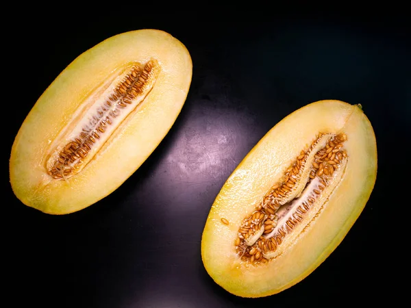 Yellow melon cut with a knife on a black background. Food photo. Melon culture. Agriculture. Place for your text. Black background. Background image. Shchablon. Poster. Vegetarian food.
