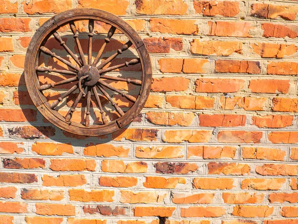 砖墙上的旧木轮 马车的木制轮子 红砖墙装饰元素 复古风格 背景图像 放在你的文字位置上 — 图库照片