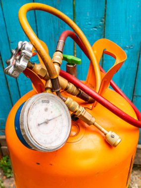 Soğutucu silindir ve basınç göstergeli hortumlar. Freonlu turuncu şişe. Buzdolabı ve klimaların tamiri için basınç göstergesi. Buzdolabı ve klima onarım aracı.