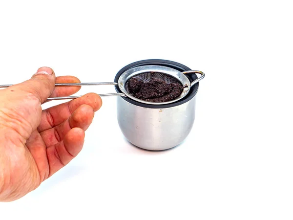 A strainer for filtering coffee or tea is poured into a cup. Metal strainer. Coffee and hot drinks. Preparing hot drinks. Filter. Kitchen dishes. Home kitchen. Tool. White background. Place for text.