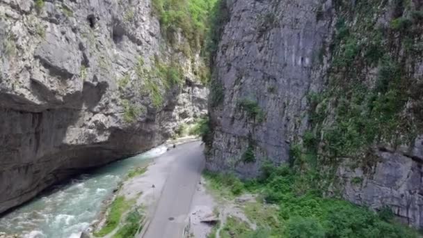 Аэросъемка горной реки и дороги в ущелье — стоковое видео