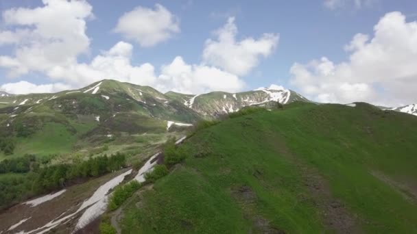 Vue aérienne de sommets de montagnes vertes avec de petites taches de neige — Video