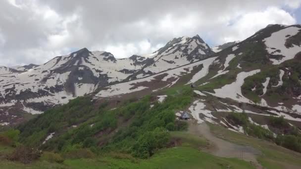 Χιονισμένες κορυφές των βουνών και δύο μικρά σπιτάκια στην κοιλάδα κεραία βολή — Αρχείο Βίντεο