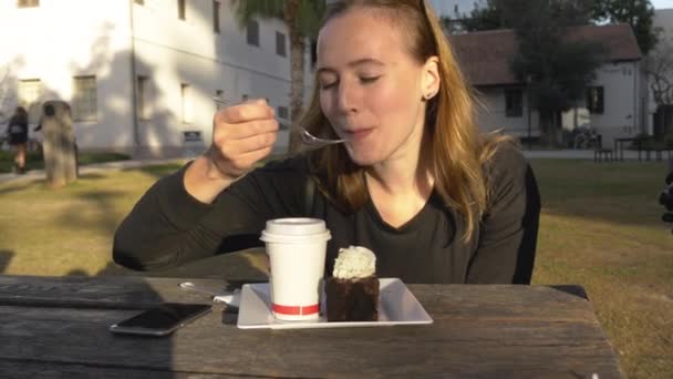 Joven mujer feliz comer pastel al aire libre en el parque — Vídeo de stock