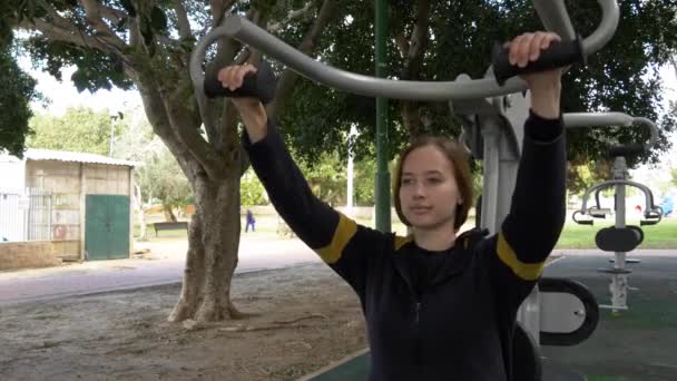 Hermosa mujer hacer ejercicios para las manos en el equipo de la calle — Vídeo de stock