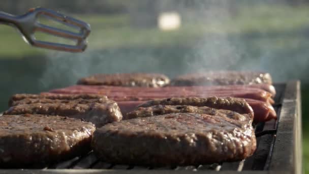 Cocinar chuletas y salchichas en la barbacoa en el parque — Vídeos de Stock