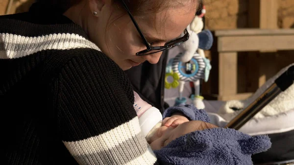 Outdoor formula feeding, small funny baby eating from the bottle