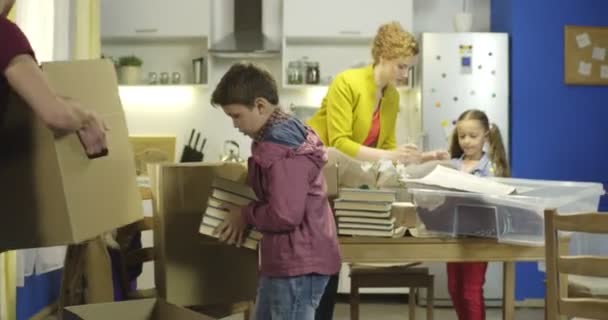 Счастливая семья распаковывает коробки на кухне — стоковое видео