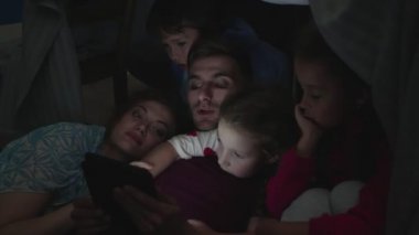 Aile sandalye ve battaniyeden yapılmış evde oturup.