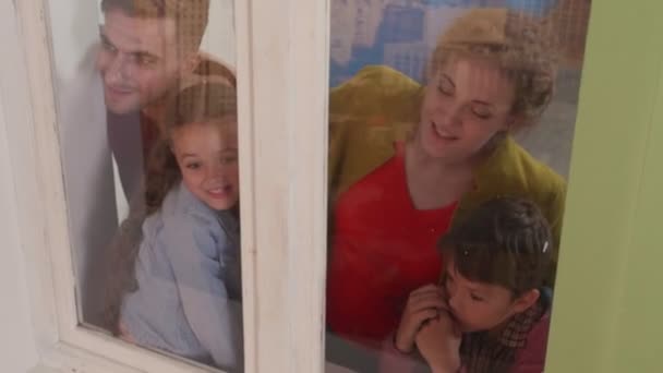 Familie staan over het raam en kijken uit het raam. — Stockvideo