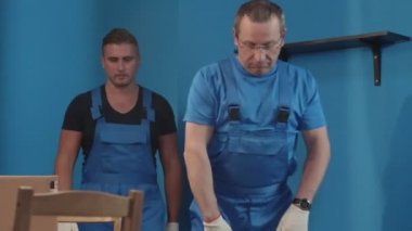 İki işçi mutfakta kutu taşıyor..