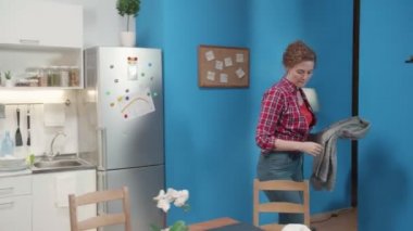 Kadın sandalyeden bir şeyler koyar.