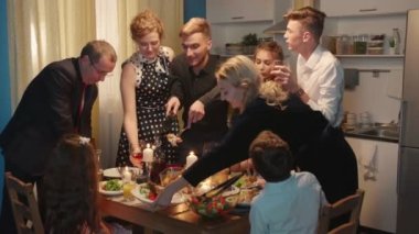 Aile ve misafirleri mutfakta yiyip içiyor.