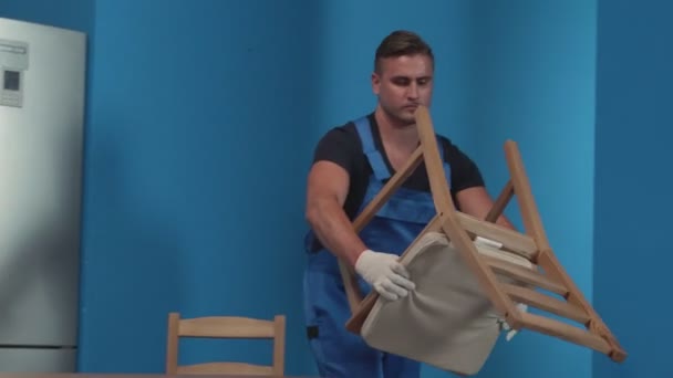 Muž přivede židli do kuchyně. — Stock video