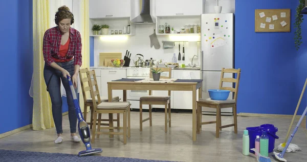 주부는 파란색 진공 청소기로 바닥과 카펫을 청소합니다.. — 스톡 사진