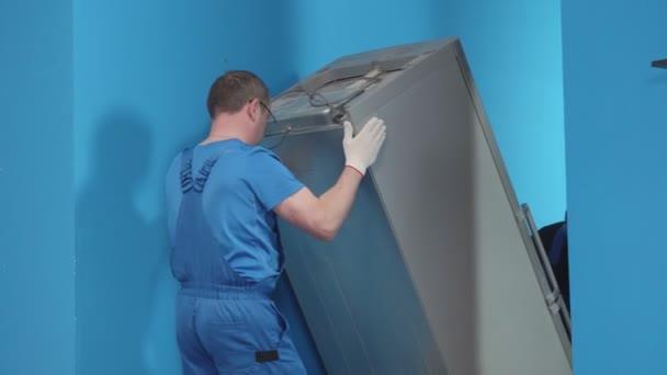 Los hombres de uniforme traen una nevera a la cocina. . — Vídeo de stock