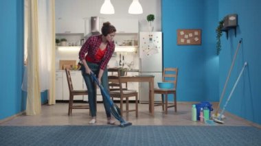 Ev hanımı bir elektrik süpürgesi ile halı temizler.