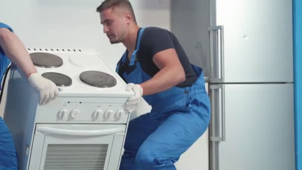 Los hombres traen una estufa a la cocina . — Vídeo de stock