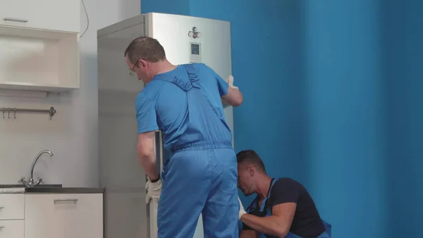 A férfiak egyenruhában vesz egy hűtőszekrény. — Stock Fotó