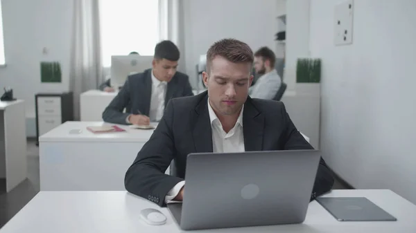 Dia comum no escritório, o homem trabalha em um laptop . — Fotografia de Stock