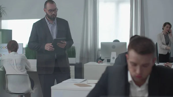 Chefe com tablet está assistindo, as pessoas estão ocupadas com o trabalho . — Fotografia de Stock