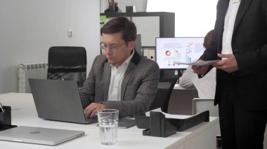 Ofisteki iki adam belgeleri tartışıyor.