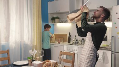 Çocuk babasına yardım eder ve elma koyar..