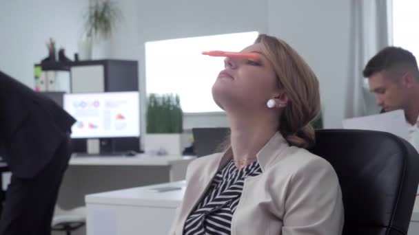 Vrouw op kantoor houden een pen op haar neus. — Stockvideo