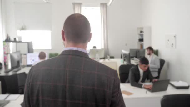 L'uomo cammina in ufficio e le persone intorno a lui lavorano . — Video Stock