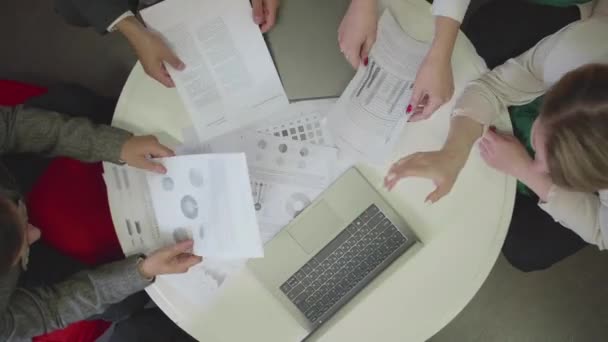 Mensen zitten aan tafel met documenten en notebook. — Stockvideo