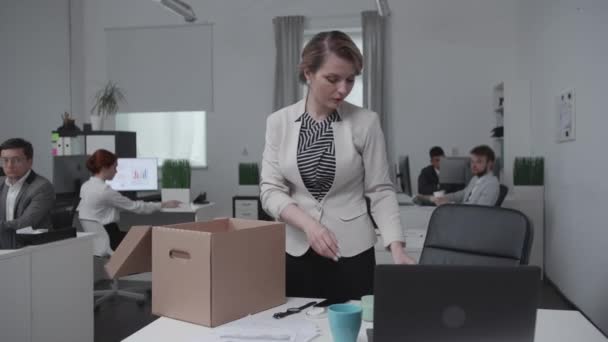 Jonge vrouw werd ontslagen en pak haar spullen, collega's achter look. — Stockvideo