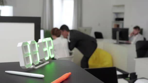 Uhr im Vordergrund, Menschen im Hintergrund im Büro. — Stockvideo