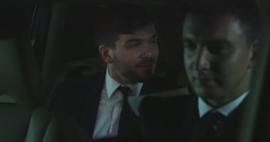 Arabanın arka koltuğunda kollegisi olan adam.