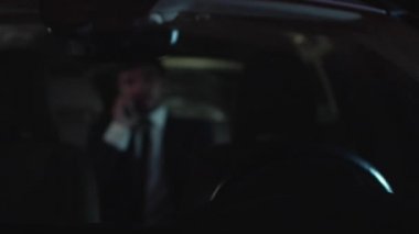 Gece kendi kendine araba kullanan adam telefonda konuşuyor.