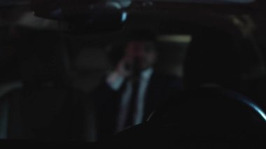 Gece kendi kendine araba kullanan adam telefonda konuşuyor.