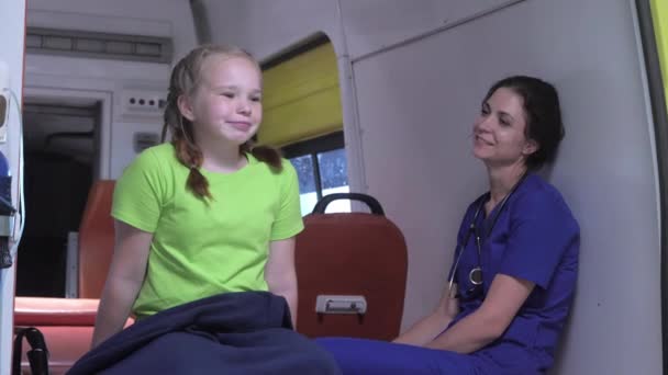 Verpleegster met klein meisje zitten in ambulance auto. — Stockvideo