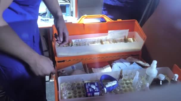 Verpleegkundige in ambulance auto zoeken naar iets in medische tas. — Stockvideo