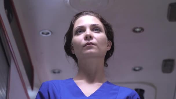 Sjuksköterska stå på bakgrunden av ambulans bil. — Stockvideo