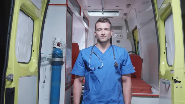 Homem de uniforme médico stand no fundo do carro de ambulância . — Fotografia de Stock