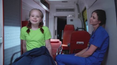 Hemşire küçük kız ile gece ambulans arabada oturup.